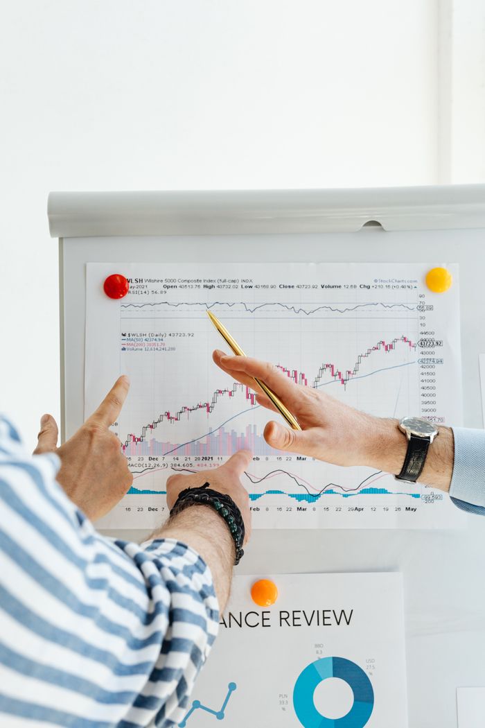 services-03 Two people analyzing financial charts on a whiteboard during a business meeting.