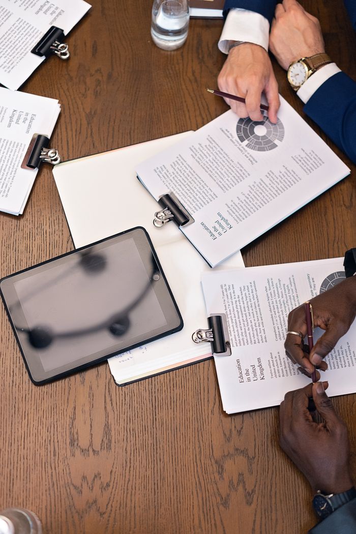 our-story Top view of a business meeting with hands, tablets, and documents on a table.